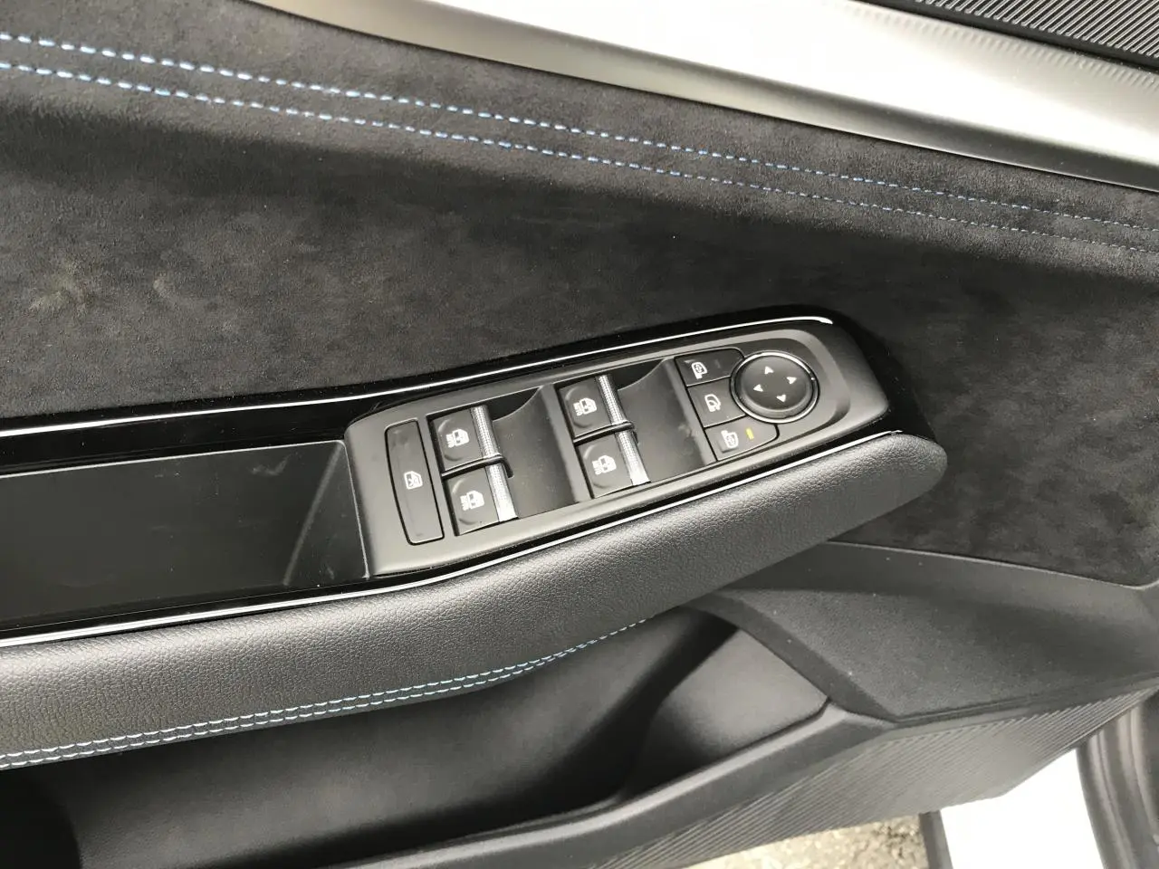 Détail de la porte côté conducteur du Renault Austral blanc, montrant les commandes des vitres et rétroviseurs avec surpiqûres bleues.