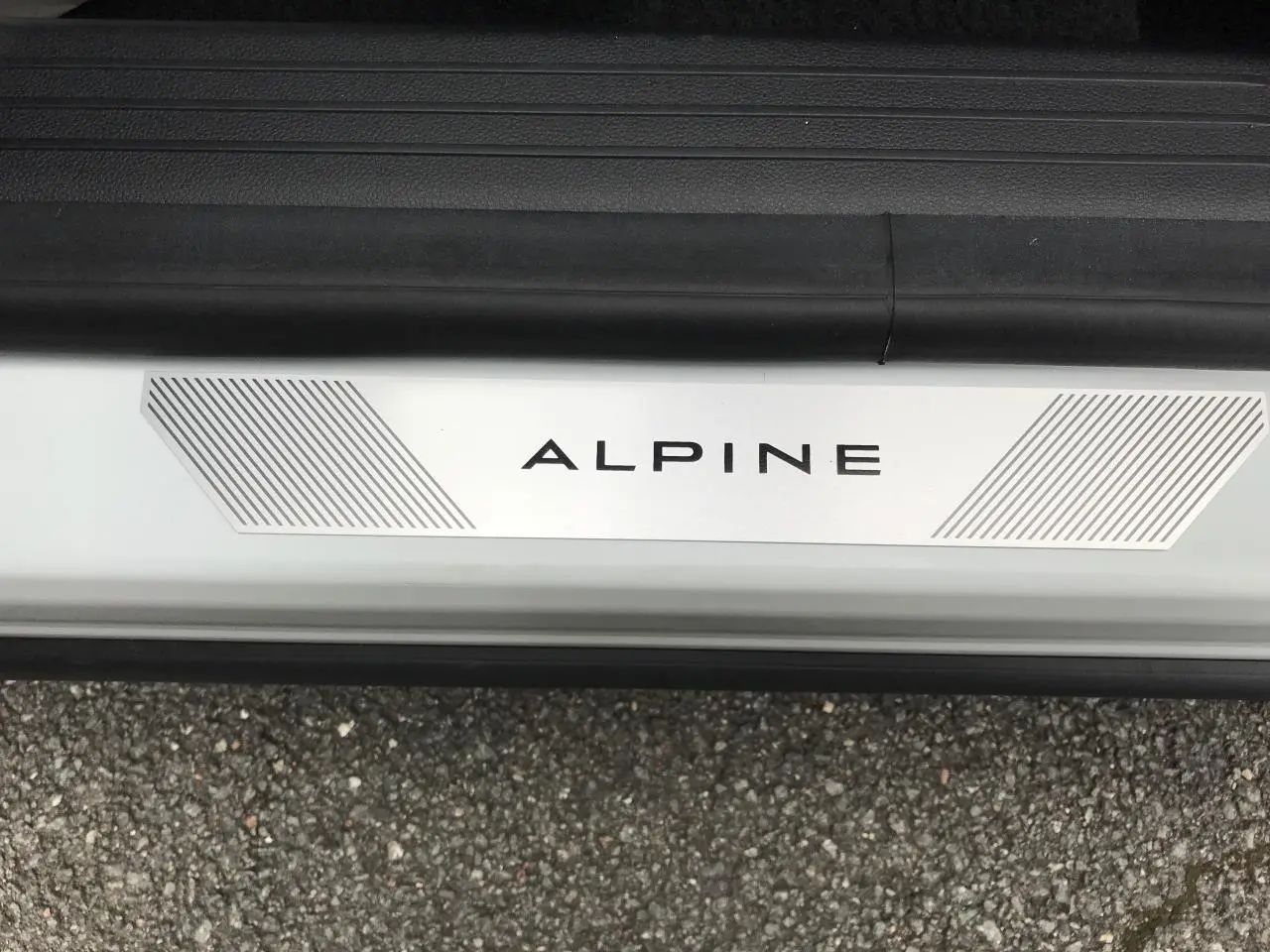Gros plan sur le seuil de porte blanc du Renault Austral Esprit Alpine avec logo ALPINE et bandes grises.