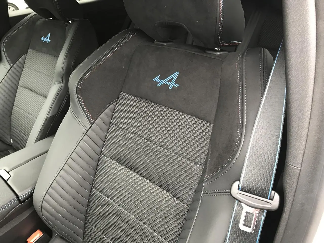 Gros plan sur les sièges avant noirs du Renault Austral Esprit Alpine avec logo bleu et surpiqûres colorées.