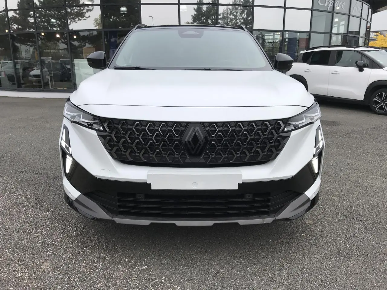 Vue de face du Renault Austral blanc avec calandre noire à motif nid d'abeille et feux LED distinctifs en forme de T.