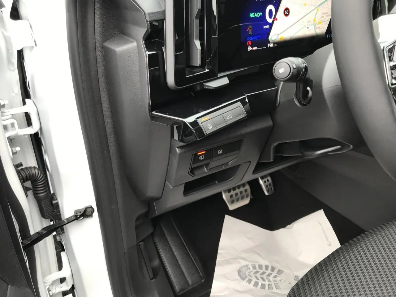 Vue intérieure côté conducteur du Renault Austral blanc, montrant les pédales, commandes électroniques et partie du tableau de bord numérique.