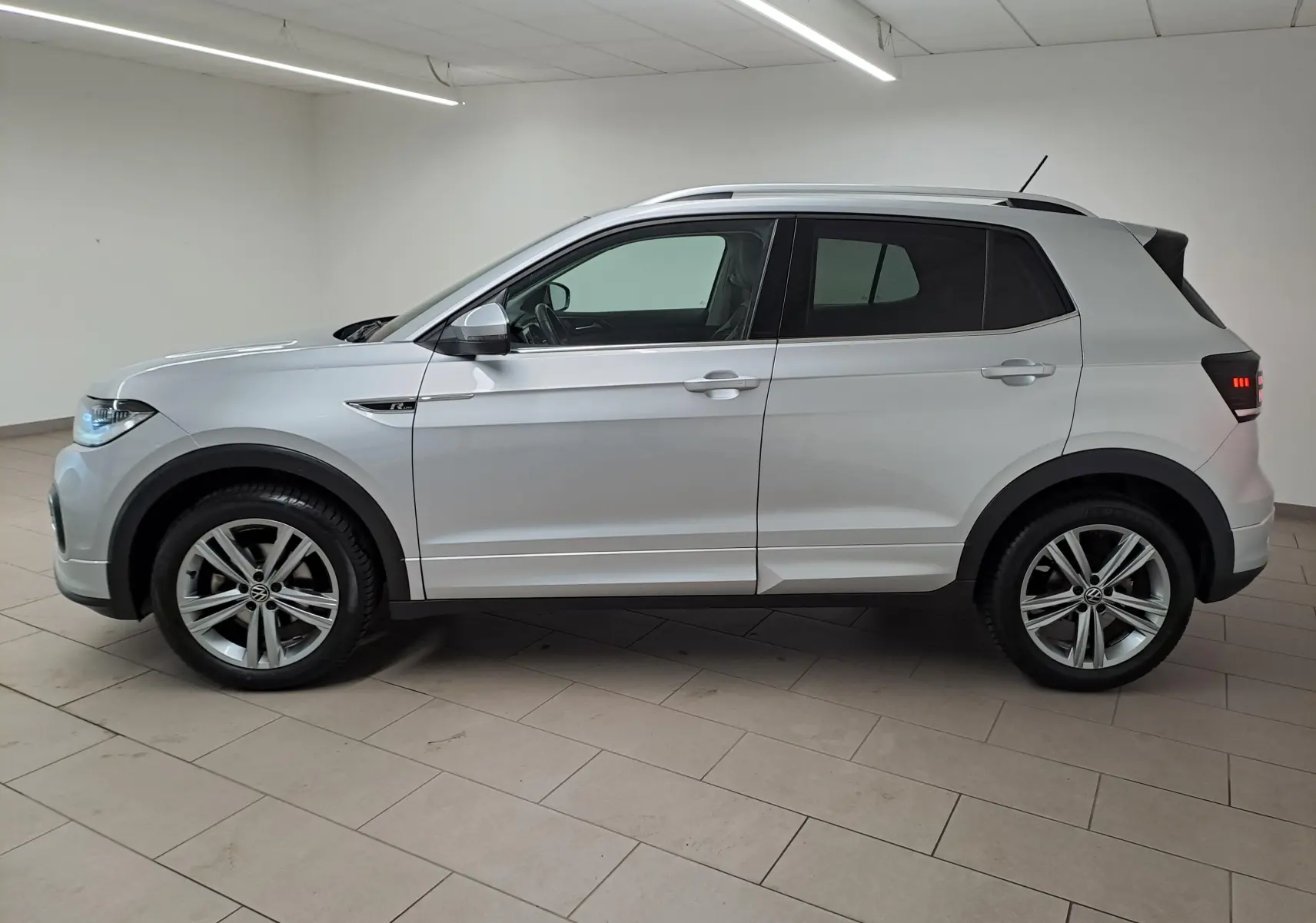 Vue de profil côté gauche d'un Volkswagen T-Cross 2022 argent Reflet d'Argent avec finition R-Line et jantes alliage.