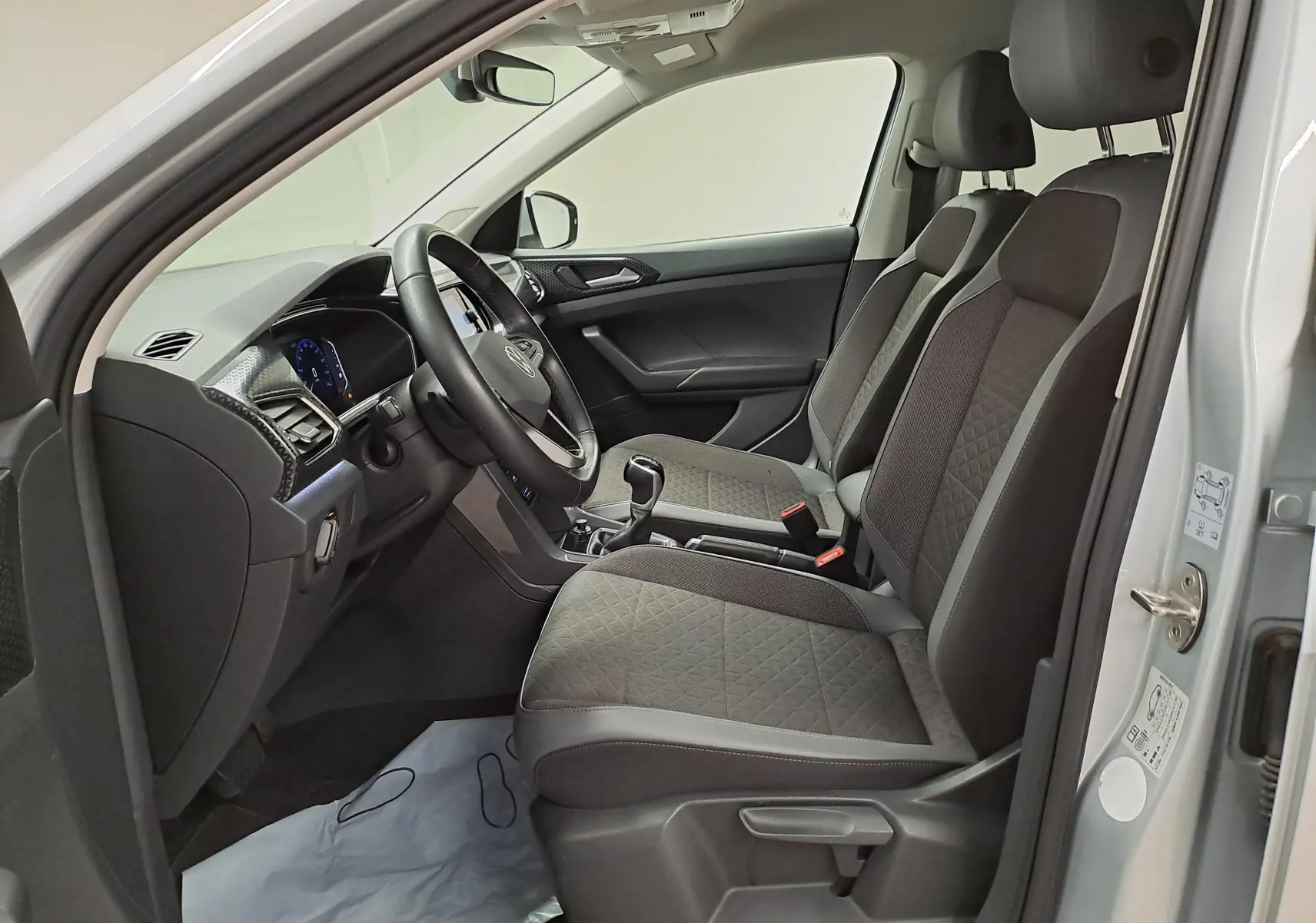 Vue intérieure côté conducteur du Volkswagen T-Cross 2022 argent, montrant sièges tissu gris et tableau de bord moderne.