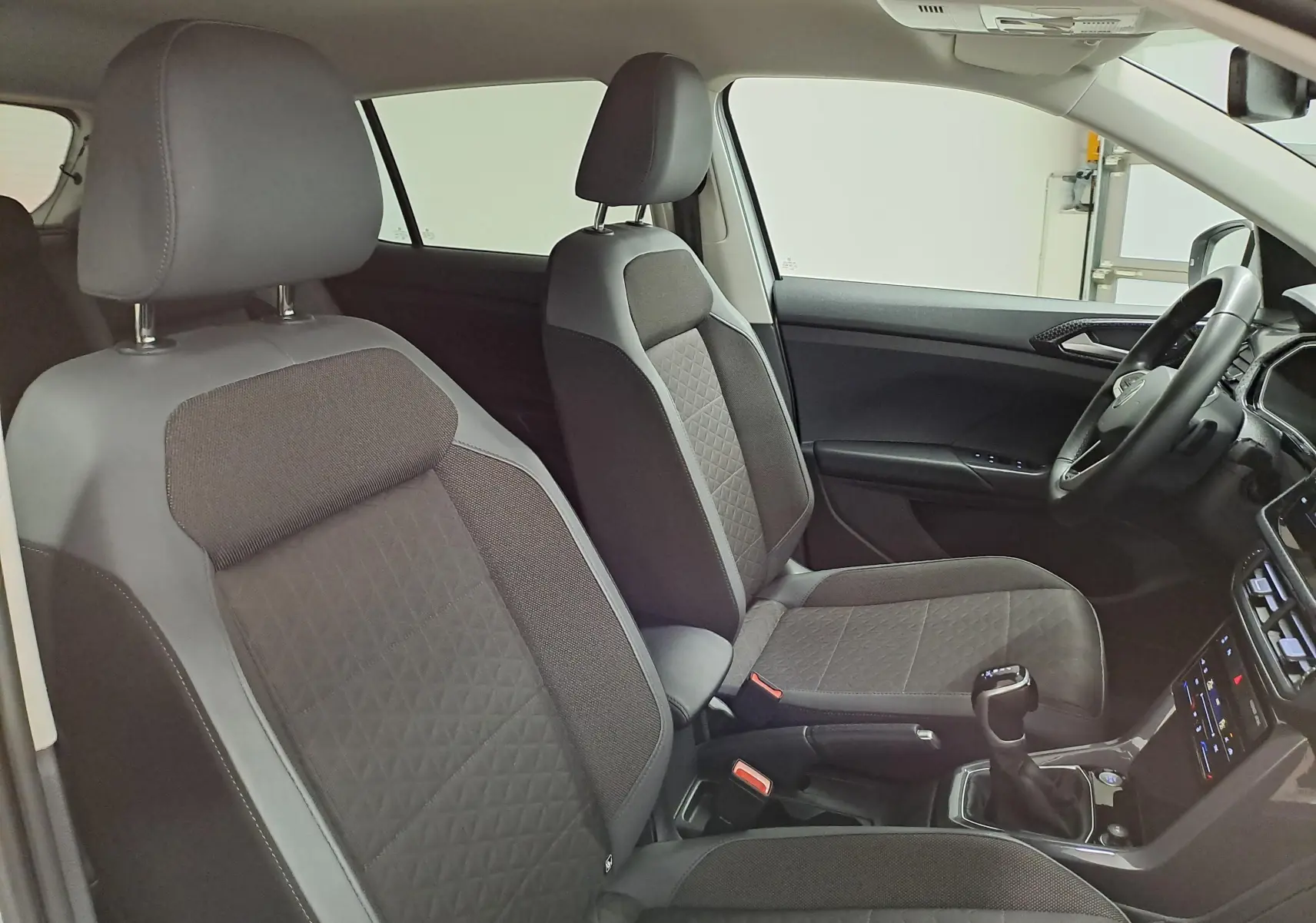 Vue intérieure côté droit du Volkswagen T-Cross 1.0 TSI R-Line 2022, sièges tissu noir avec surpiqûres et console centrale.