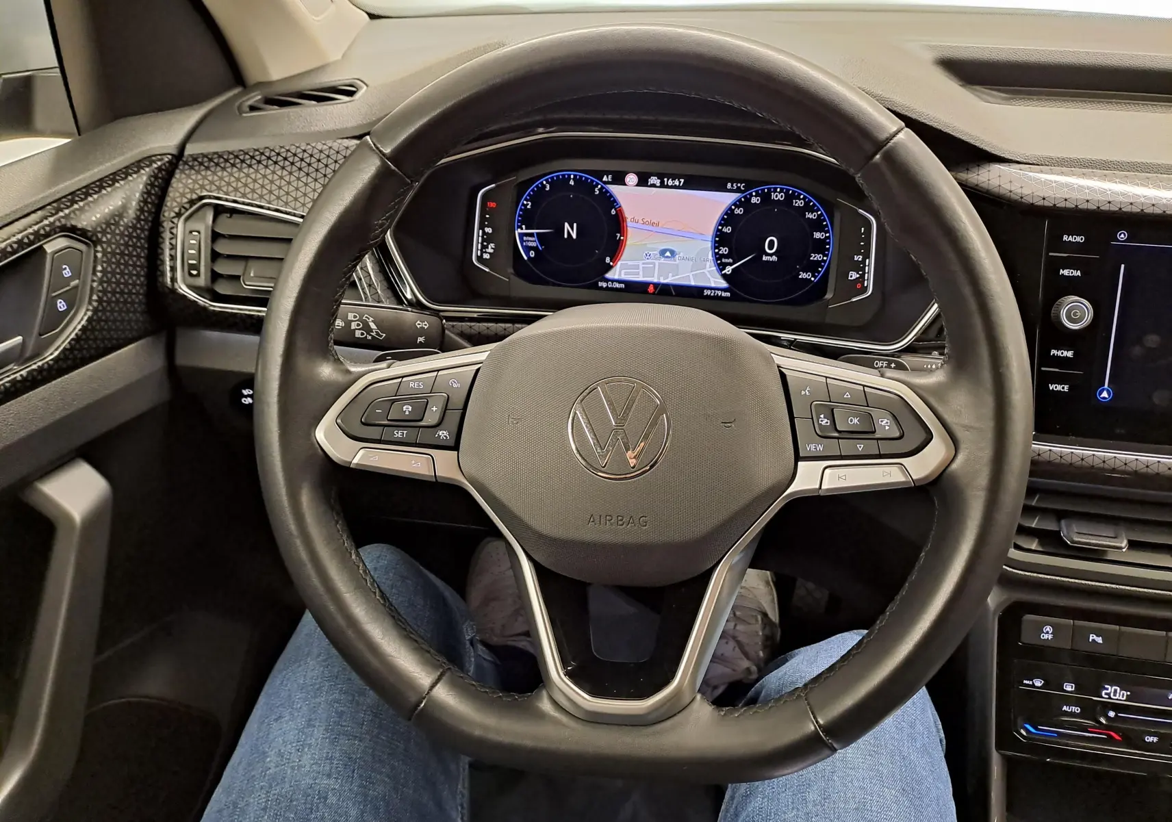 Vue intérieure centrée sur le volant noir du Volkswagen T-Cross 2022 R-Line avec tableau de bord digital et détails argentés.