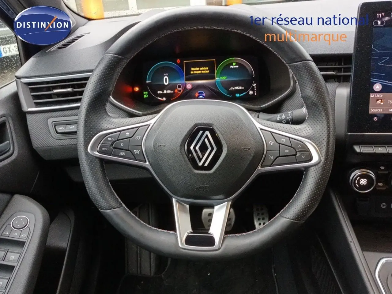 Vue intérieure centrée sur le volant noir perforé de la Renault Clio 1.6 E-TECH 2024 avec tableau de bord numérique et écran tactile.