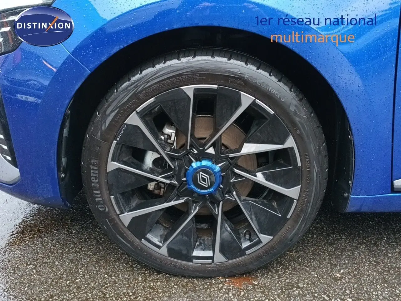 Gros plan sur la roue avant gauche d'une Renault Clio 2024 bleu iron metal avec jante noire et argentée.
