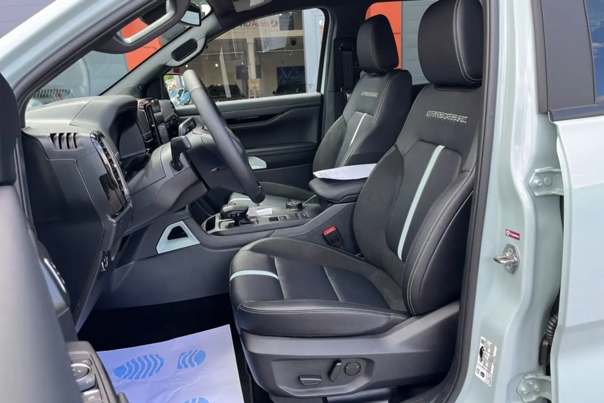 Vue intérieure côté conducteur du Ford Ranger 2.3 PHEV gris zen, sièges Stormtrak noirs avec surpiqûres blanches.