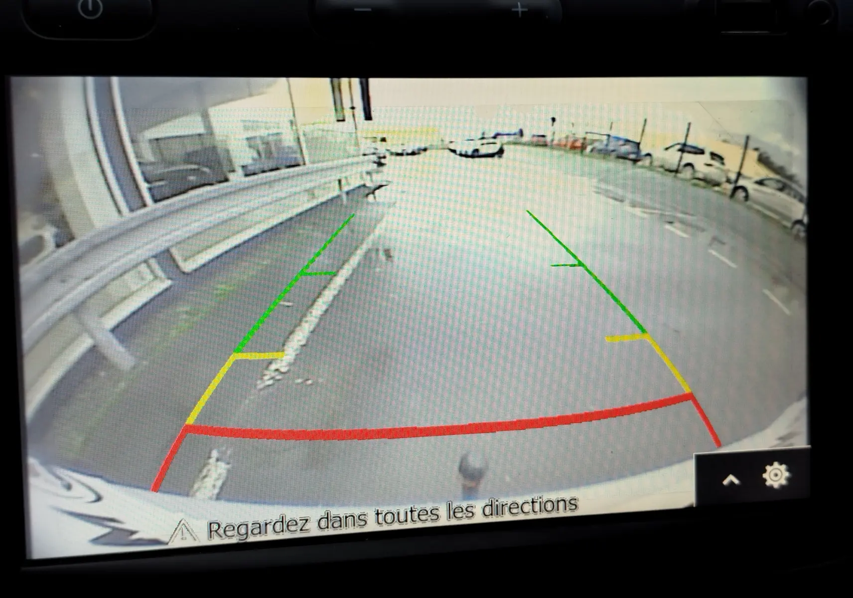 Vue caméra de recul du Dacia Duster rouge Fusion 2020, montrant les lignes de guidage colorées sur un parking extérieur.