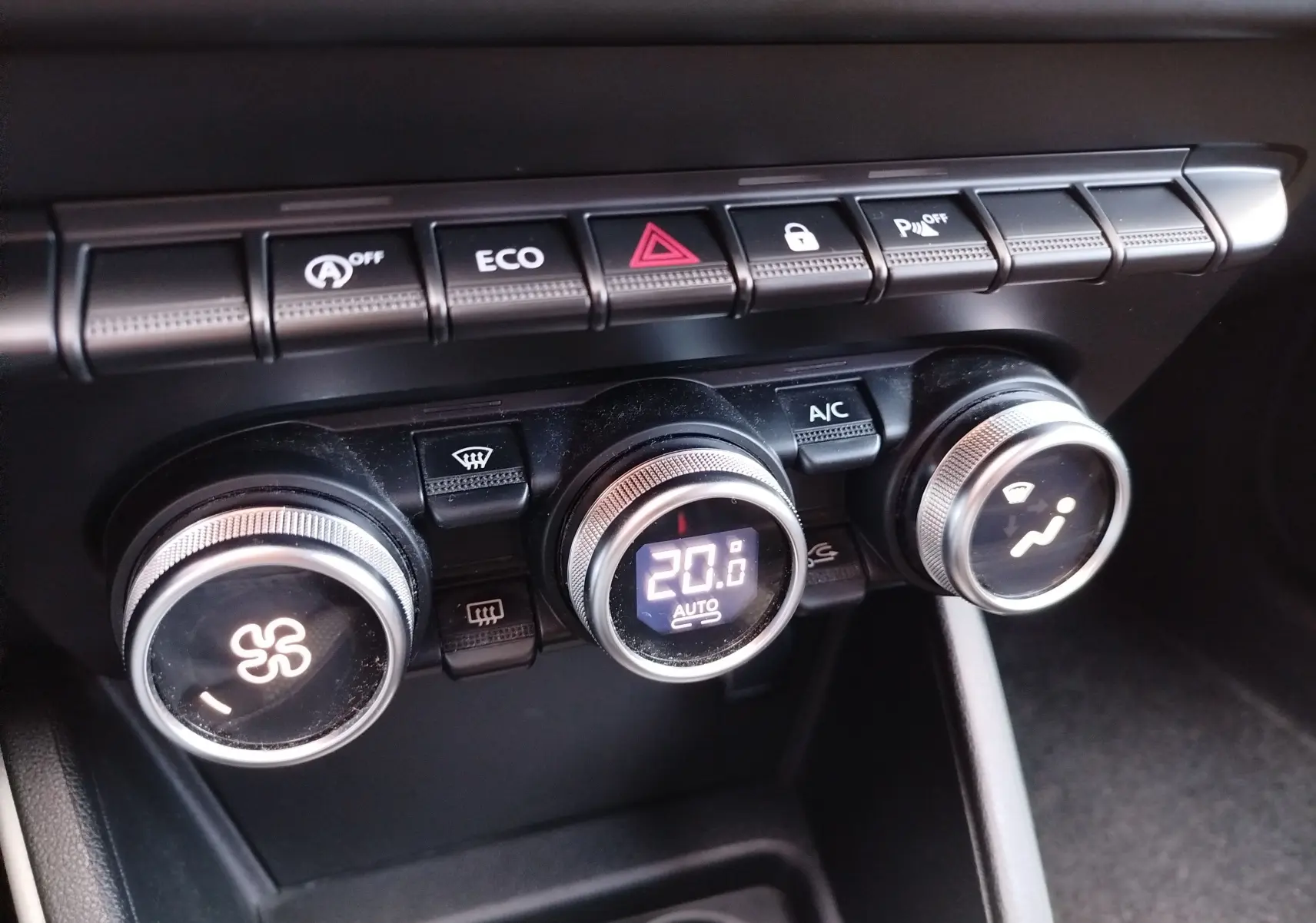 Gros plan sur la console centrale du Dacia Duster 2020, montrant les commandes de climatisation et les boutons de fonction.