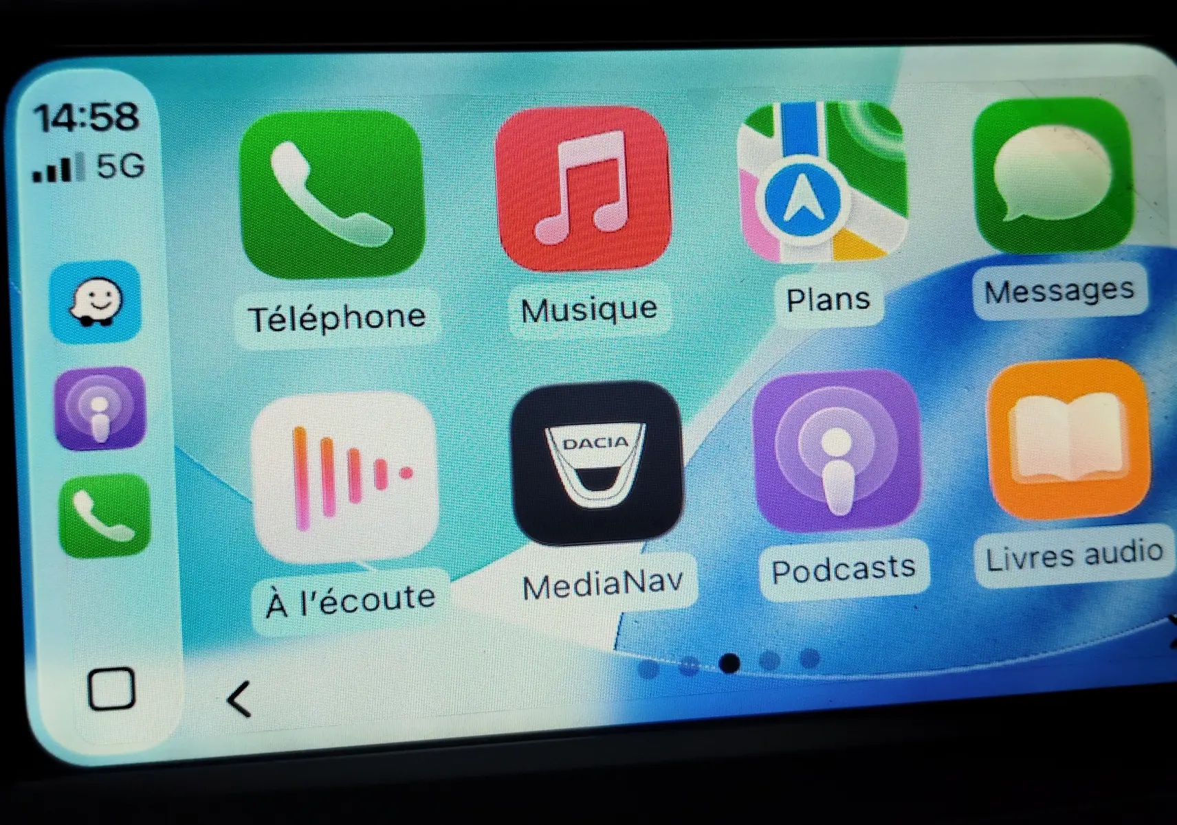 Écran tactile du système MediaNav de Dacia affichant plusieurs applications, avec l'icône Dacia au centre.