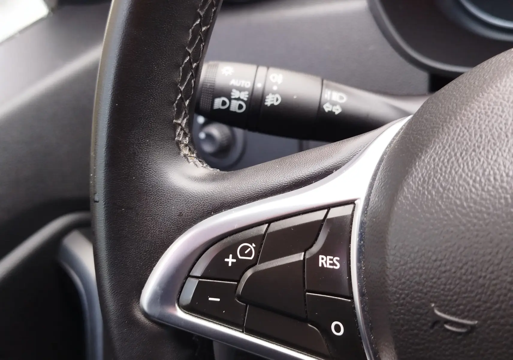 Gros plan sur les commandes au volant gauche du Dacia Duster 2020 rouge, avec boutons de régulateur de vitesse visibles.