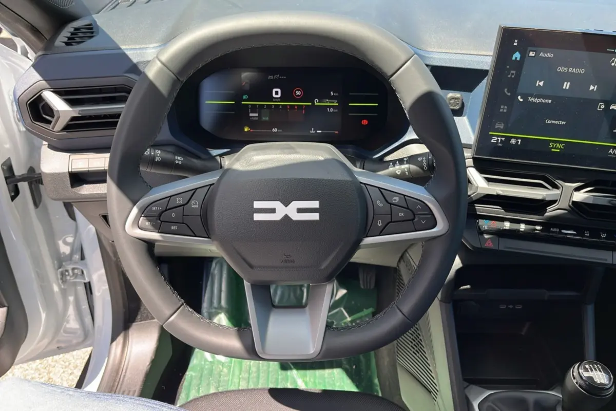 Vue intérieure centrée sur le volant cuir et le tableau de bord numérique du Dacia Bigster blanc glacier 2025.