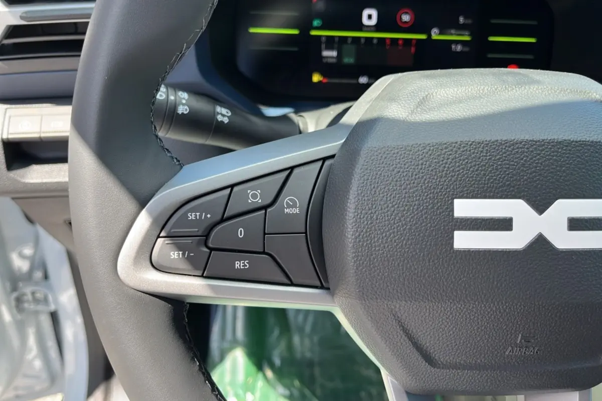 Gros plan sur le volant cuir du Dacia Bigster 2025 avec commandes multifonctions et tableau de bord numérique en arrière-plan.