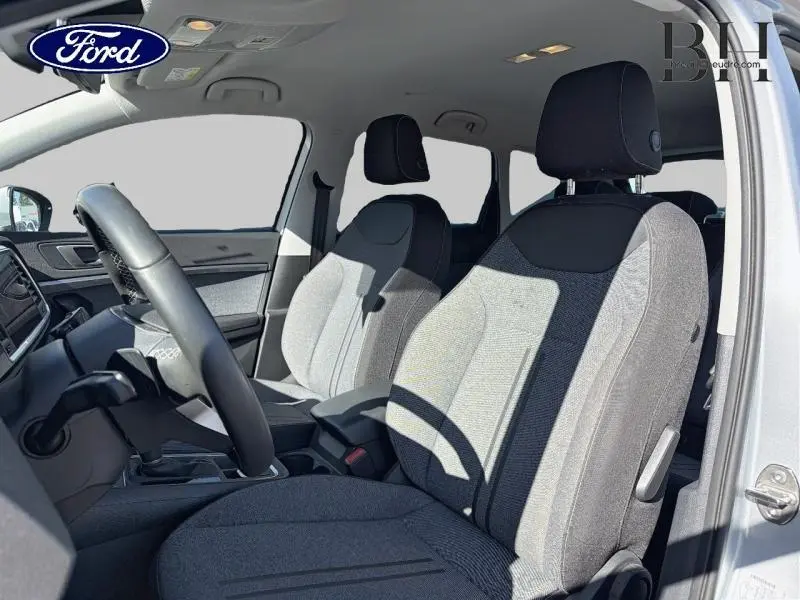 Vue intérieure côté conducteur du SEAT Ateca 2023, sièges tissu gris et volant cuir multifonction.