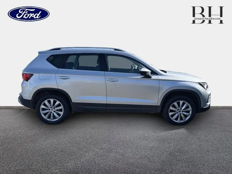 Vue de profil côté gauche du SEAT Ateca 2023 argent Reflex Métal avec jantes alliage et hayon électrique visible.