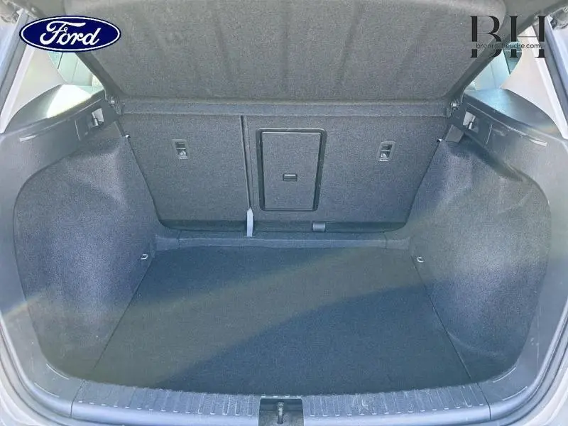 Coffre ouvert vu de l'arrière d'un SEAT Ateca 2023 argent Reflex Métal, espace de chargement vide et habillage tissu gris.