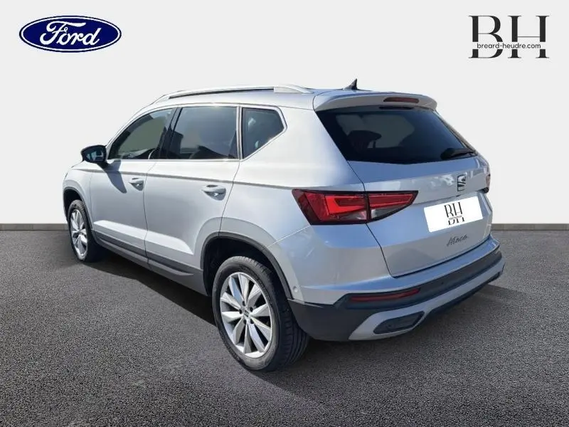 Vue 3/4 arrière droite d'un SEAT Ateca 2023 argent Reflex Métal avec hayon électrique et vitres arrière surteintées.