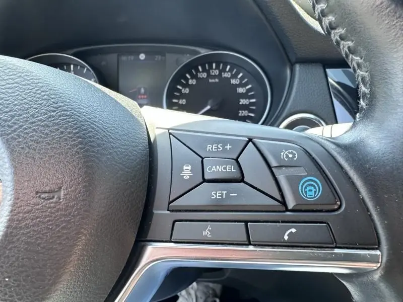 Gros plan sur les commandes au volant côté droit du Nissan Qashqai blanc 2019, avec régulateur de vitesse et affichage du tableau de bord.