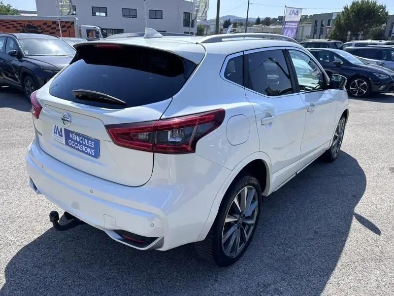 Vue 3/4 arrière droite d'un Nissan Qashqai blanc 2019 avec toit noir et jantes alliage, stationné en extérieur.