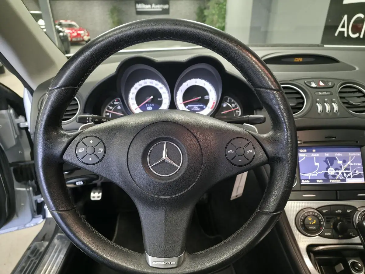 Vue intérieure centrée sur le volant cuir noir AMG d'une Mercedes SL 350 gris, avec tableau de bord et écran de navigation visibles.