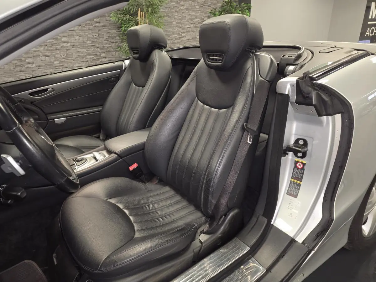 Vue intérieure côté conducteur de la Mercedes SL 350 gris, sièges cuir noirs et console centrale visible.