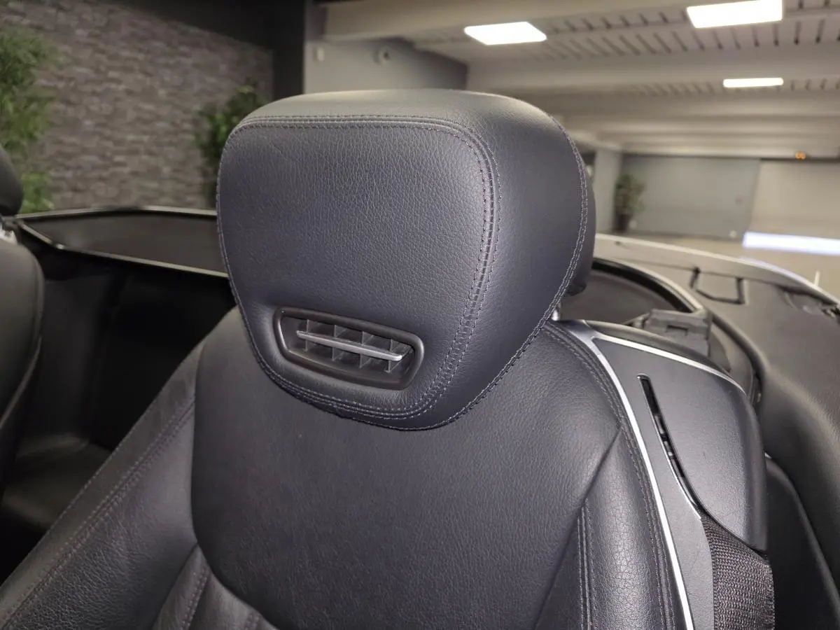 Gros plan sur l’appuie-tête en cuir noir du siège avant droit d’une Mercedes SL 350 gris, intérieur ouvert.