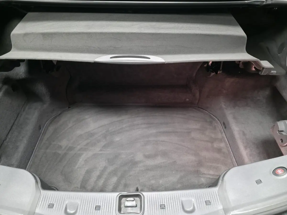 Vue plongeante sur le coffre spacieux et propre d'une Mercedes SL 350 gris, avec cache-moyeu bleu visible.