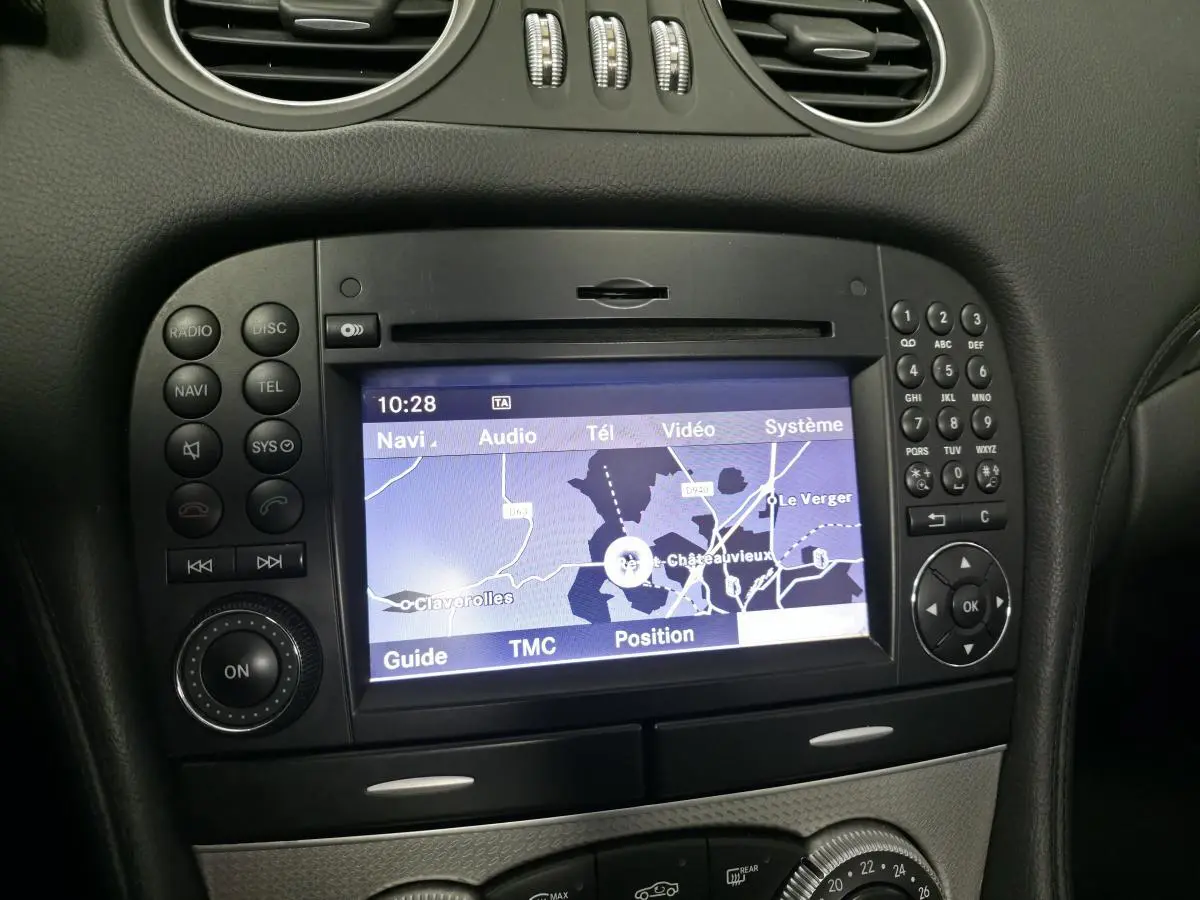 Vue rapprochée de l’écran de navigation COMAND APS et des commandes noires du tableau de bord intérieur d’une Mercedes SL gris 2009.