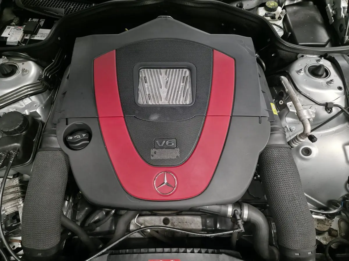 Vue plongeante sur le moteur V6 Mercedes SL 350 avec cache moteur gris et rouge, détail du compartiment moteur.