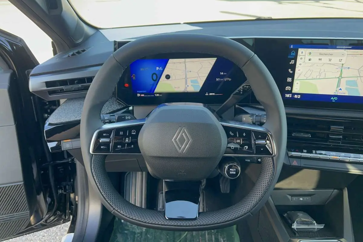 Vue intérieure centrée sur le volant multifonctions de la Renault Clio noir étoilé avec tableau de bord digital et écran tactile.