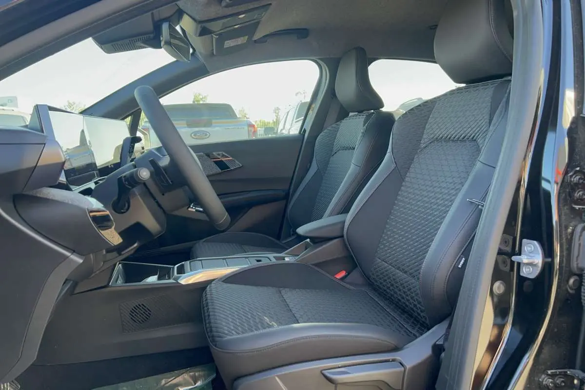 Intérieur avant droit de la Renault Clio 6 TCE 115 EDC Techno 2026 noir étoilé, sièges tissu noir avec surpiqûres.