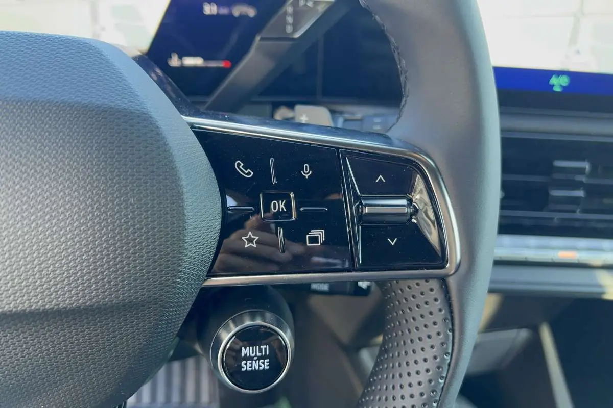 Gros plan sur le volant textile grainé de la Renault Clio noir étoilé, avec commandes multifonctions et bouton Multi Sense.