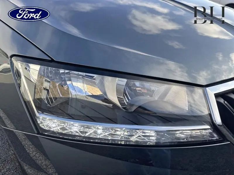 Gros plan sur le phare avant droit gris météore d'une Skoda Fabia 2021, avec détails LED et reflets du ciel.