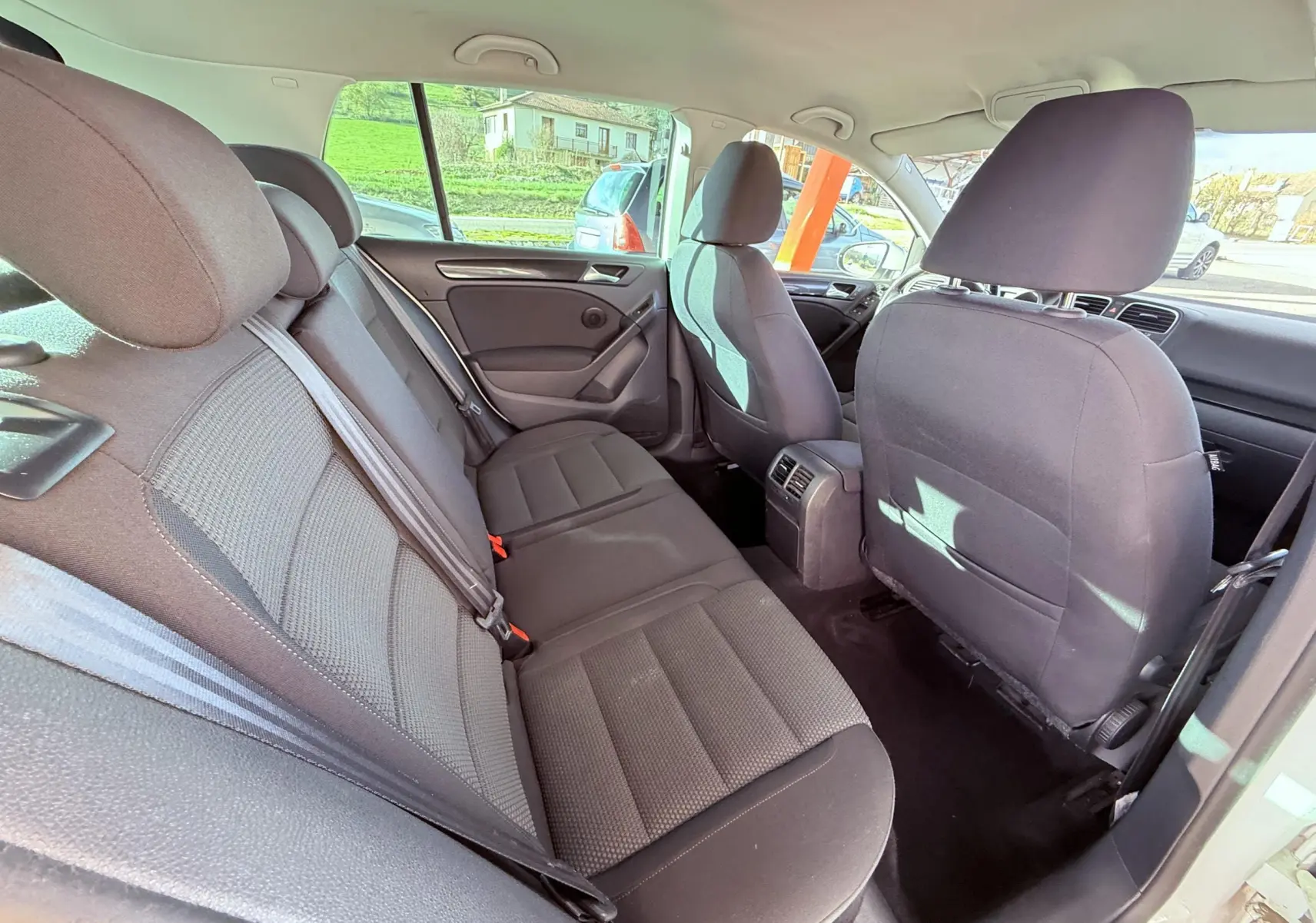 Vue intérieure arrière côté gauche montrant les sièges en tissu gris-noir d'une Volkswagen Golf blanche de 2012.