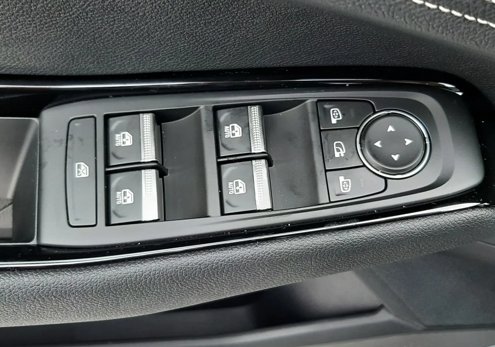 Gros plan sur les commandes de lève-vitres et rétroviseurs côté conducteur du Renault Austral gris schiste 2025.