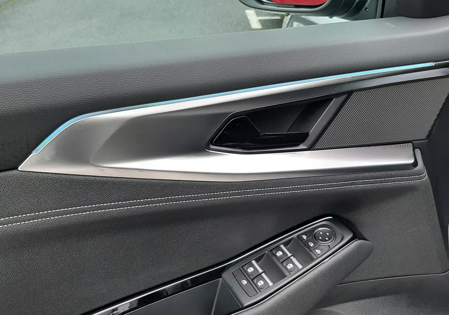 Intérieur côté conducteur du Renault Austral gris schiste, avec commandes de vitres et rétroviseur latéral visible.