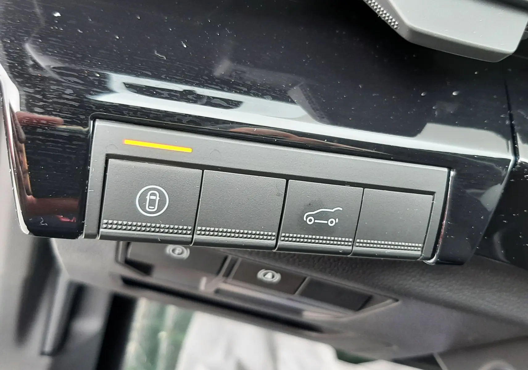 Gros plan sur les boutons de commande intérieurs du Renault Austral gris schiste, avec éclairage orange sur le bouton de verrouillage.