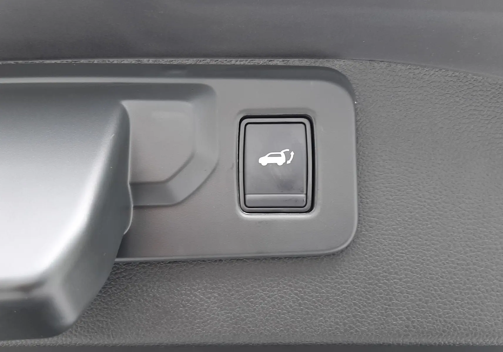 Bouton d'ouverture électrique du hayon sur la partie intérieure du coffre du Renault Austral gris schiste.