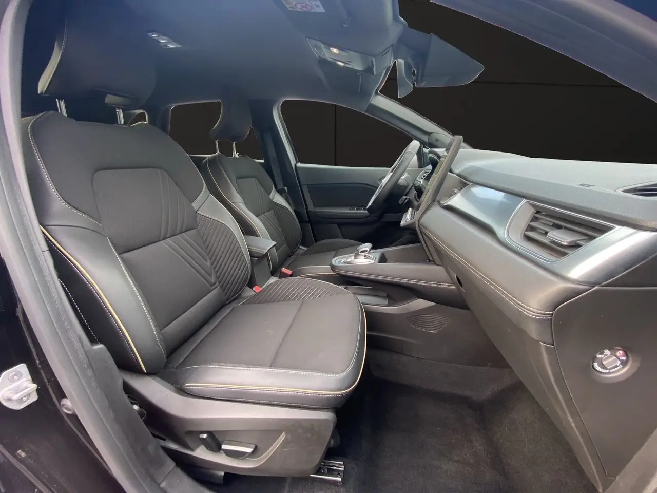 Vue intérieure côté gauche de la Renault Symbioz 2025, sièges tissu noir étoile avec surpiqûres claires et tableau de bord moderne.