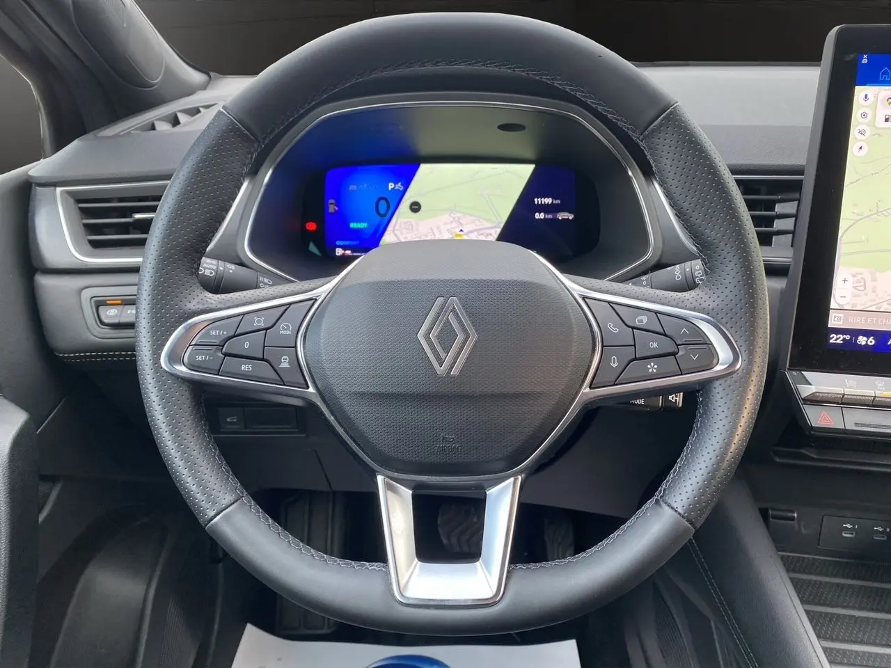 Vue intérieure centrée sur le volant noir perforé de la Renault Symbioz 2025 avec tableau de bord digital et écran tactile.