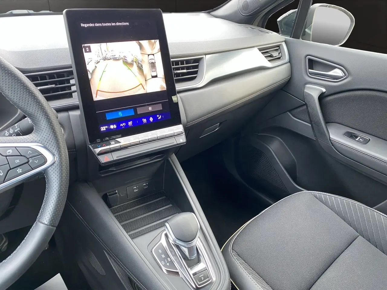 Vue intérieure côté passager du Renault Symbioz 2025, avec écran tactile central affichant la caméra de recul et console noire moderne.