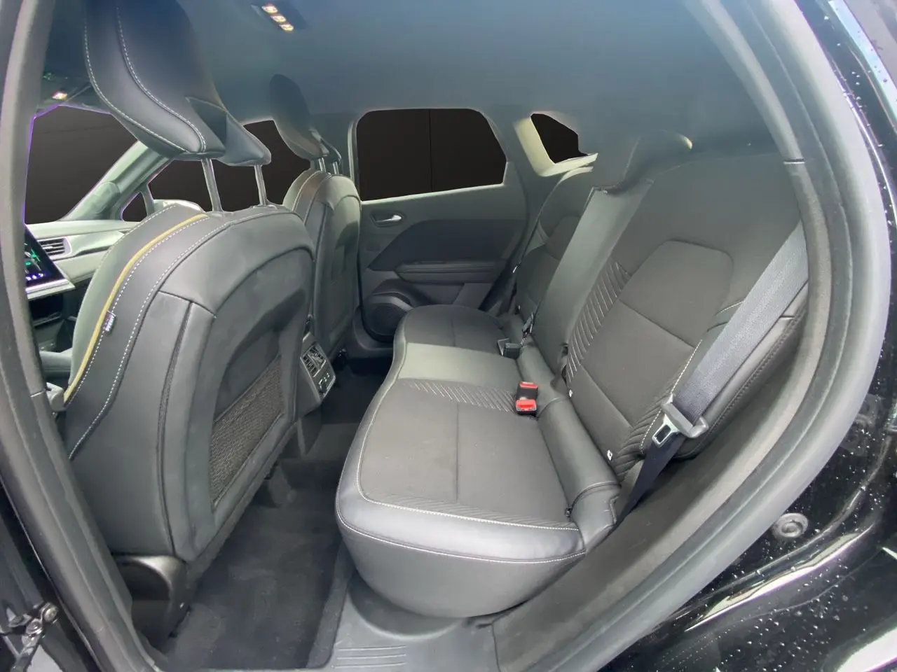Vue intérieure arrière droite de la Renault Symbioz 2025 noire étoile, sièges en tissu noir avec surpiqûres contrastées.