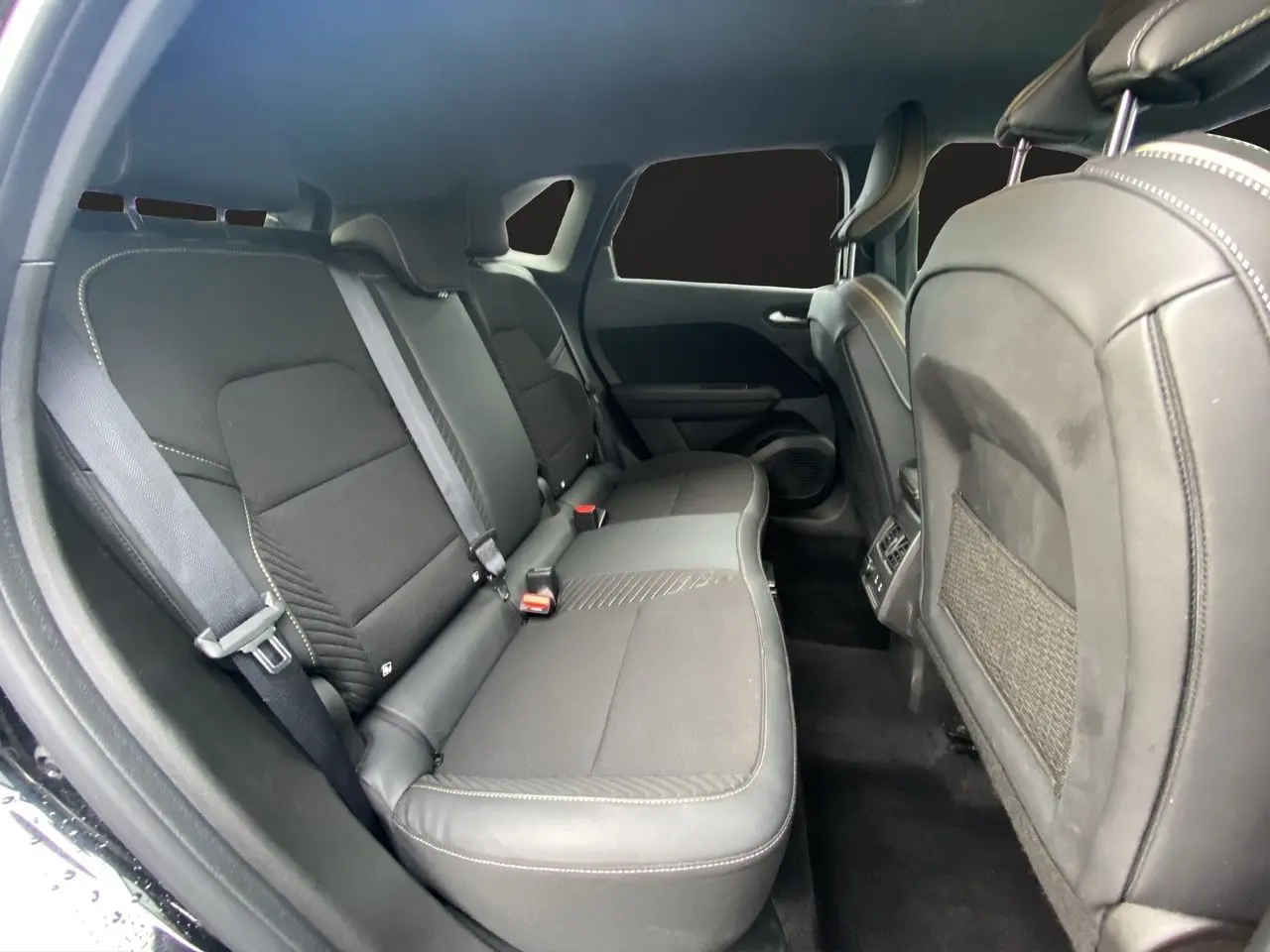 Vue intérieure côté gauche des sièges arrière noirs étoile du Renault Symbioz 2025, avec ceintures et finitions en tissu et cuir.