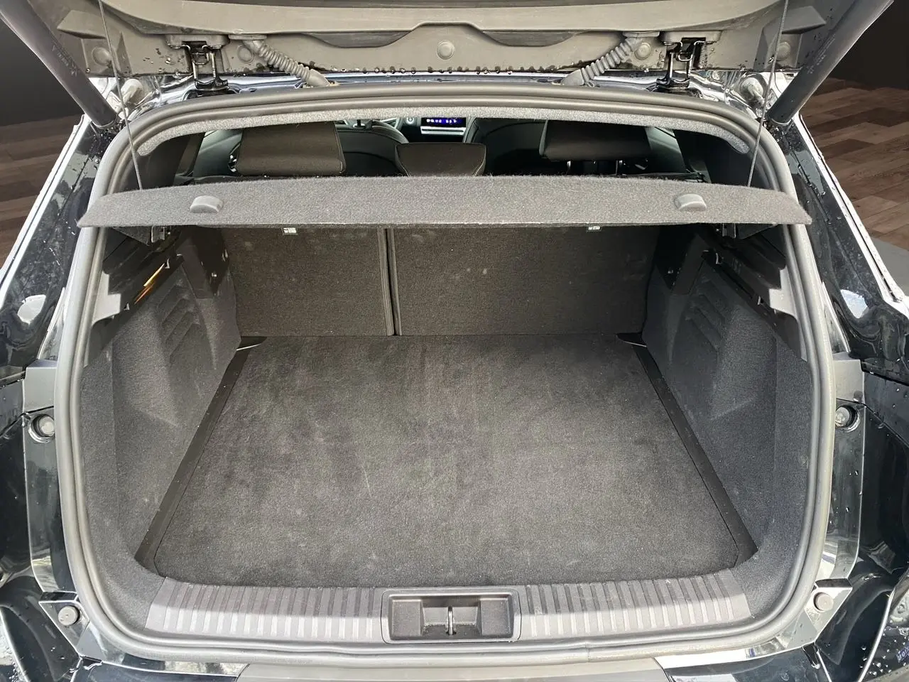 Coffre ouvert vu de l'arrière d'une Renault Symbioz noire étoile, montrant un espace de chargement propre et spacieux.