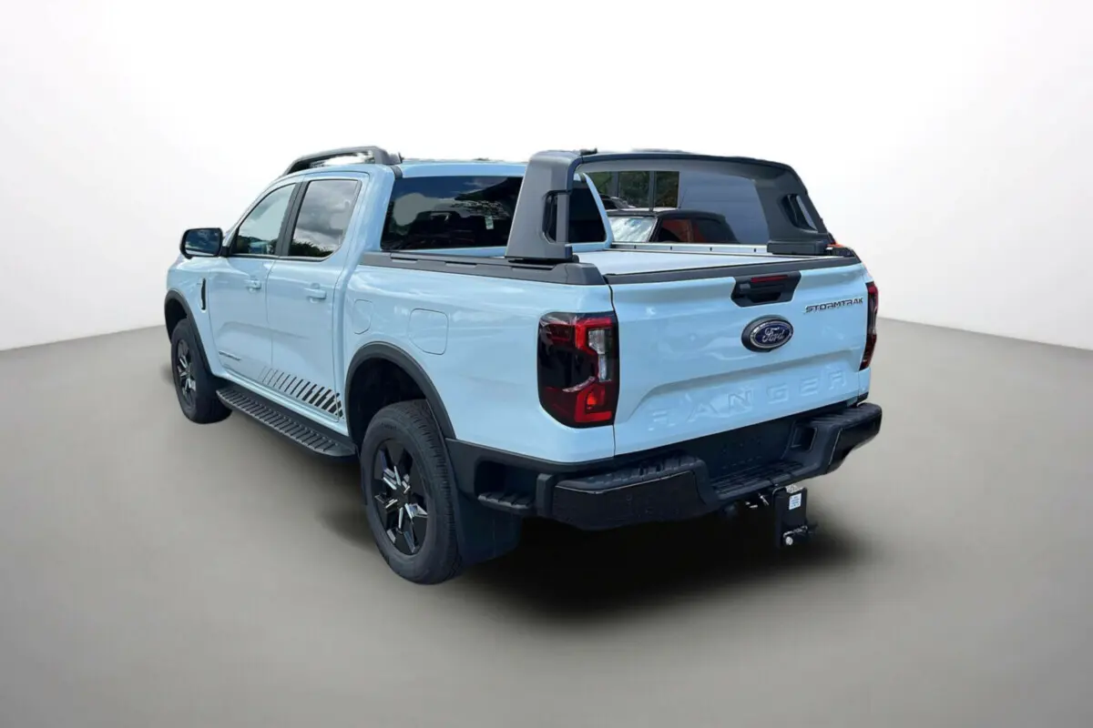 Vue 3/4 arrière droite du Ford Ranger Stormtrak 2.3 PHEV gris zen avec arceau sport et attelage visible.