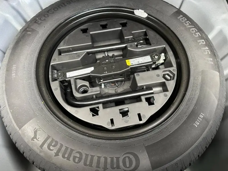 Vue rapprochée de la roue de secours Continental et du cric dans le coffre d’une Renault Clio Gris Schiste 2023.