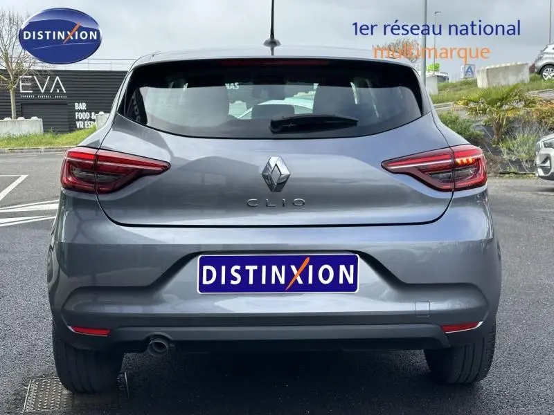 Vue arrière d'une Renault Clio gris schiste 2023 avec feux LED et logo distinctif sur un parking extérieur.
