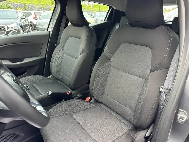 Vue intérieure côté conducteur de la Renault Clio 2023 gris schiste, montrant les sièges avant en tissu avec détails géométriques.
