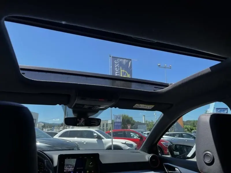 Vue intérieure du toit ouvrant panoramique d'une SEAT Ibiza 1.5 TSI bleu foncé, avec tableau de bord et ciel dégagé visible.